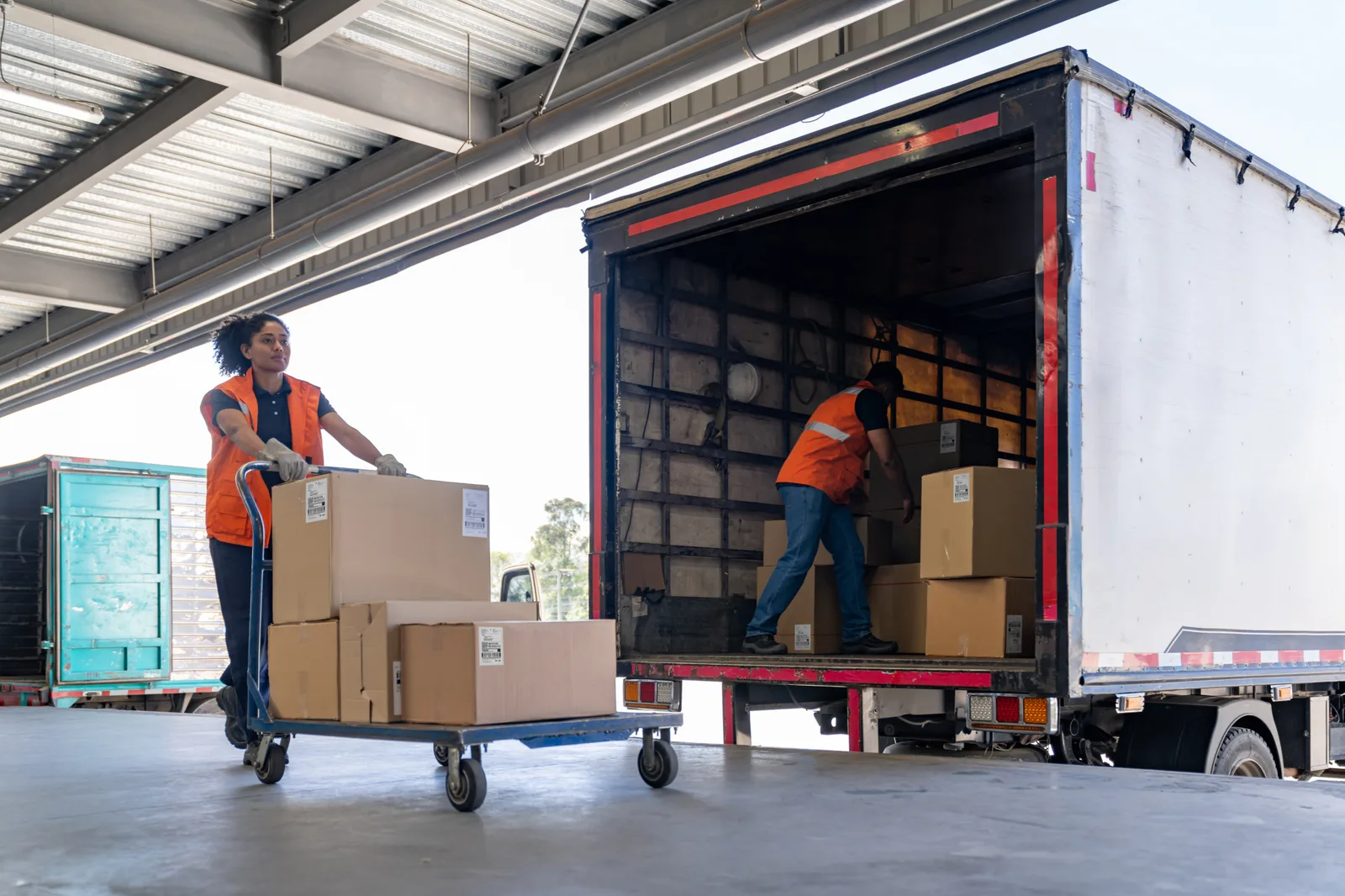 A team of warehouse workers loads boxes onto a 26-foot box truck.