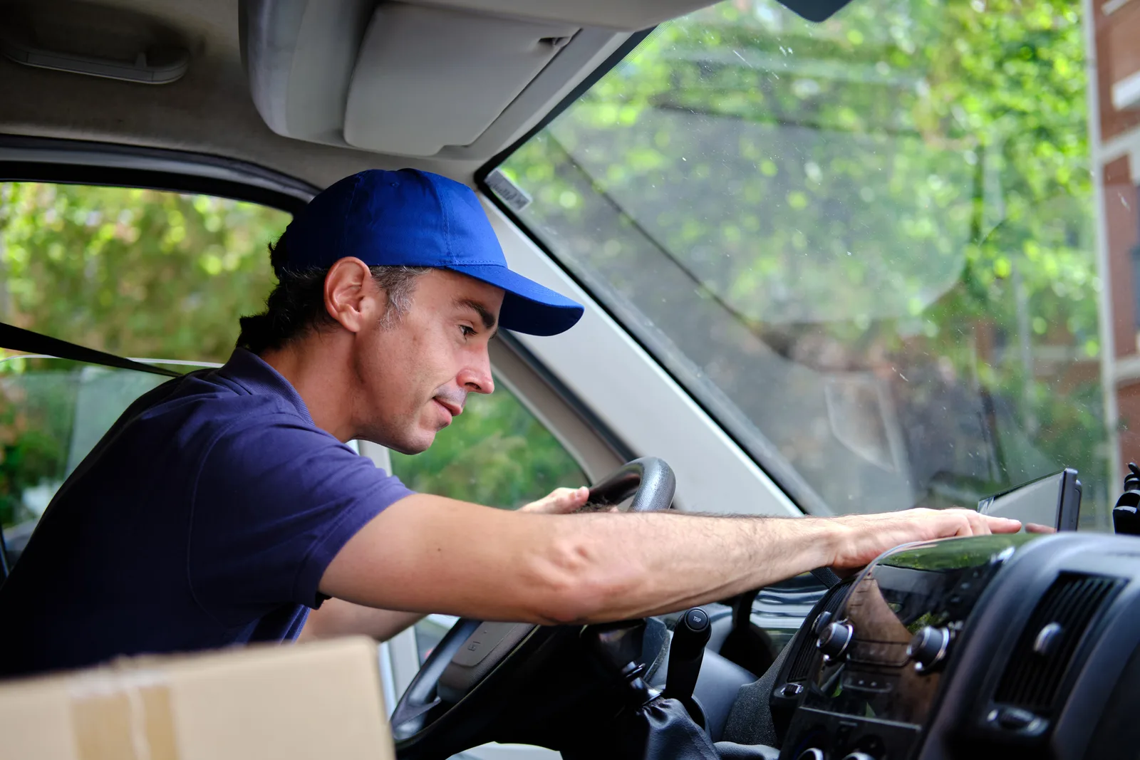 A driver sets the route on the GPS from the driver’s seat of a delivery van.
